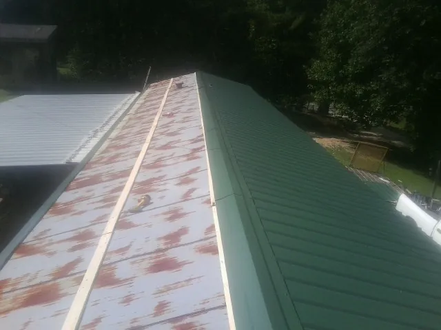 Old rusted panels beside newly installed green metal roofing — Wind Damage Roof Repair by Roofing Brothers in Fort Walton Beach