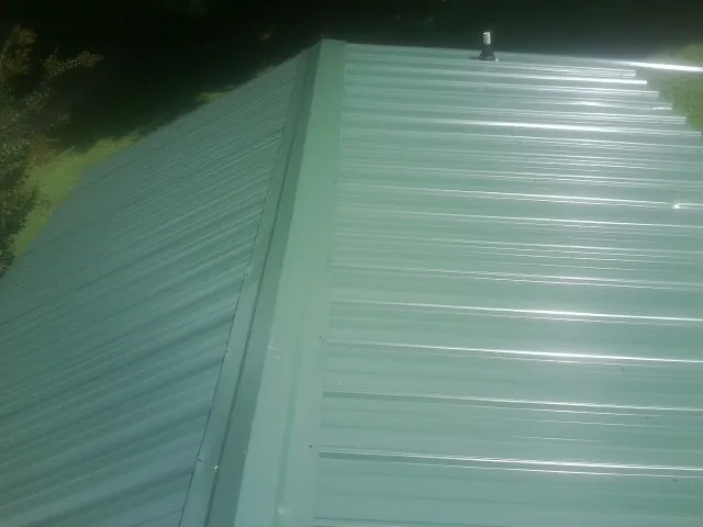 New green metal panels meeting at the ridge of a roof — Flat Roof Repair work by our crew in Fort Walton Beach