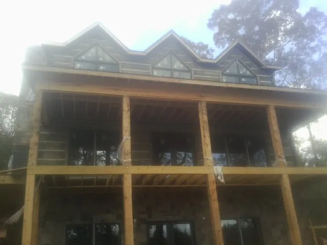 Dormers and porch framing on a large log home under construction — Roof Coating work by our crew in Fort Walton Beach
