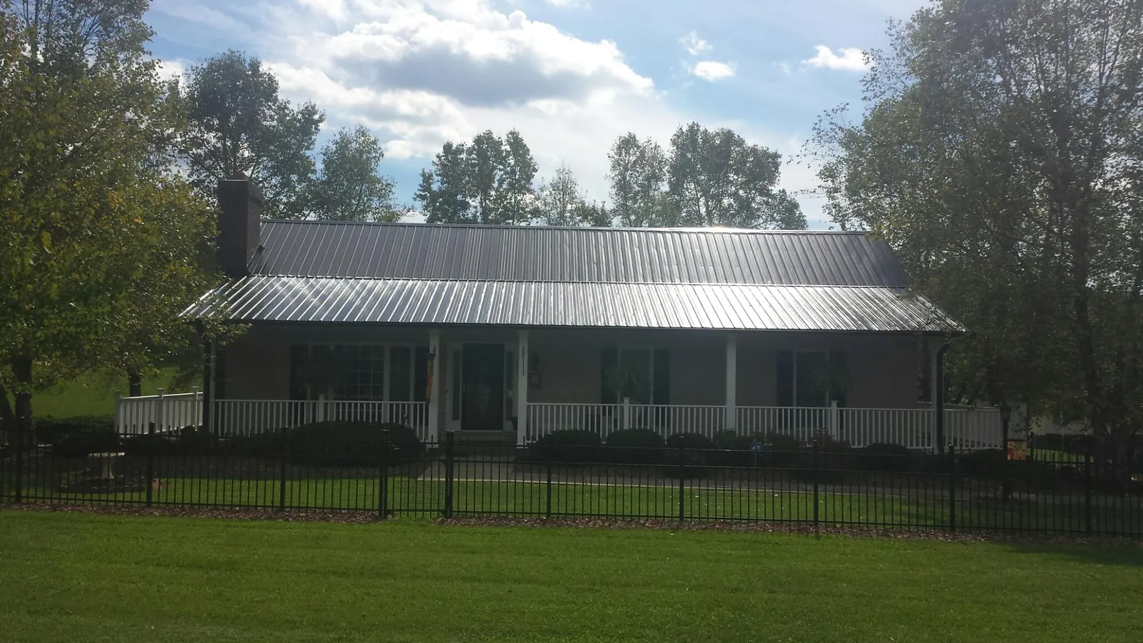 Gray metal roof on a brick ranch with a full width front porch — Gutter Guard Installation work by our crew in Fort Walton Beach