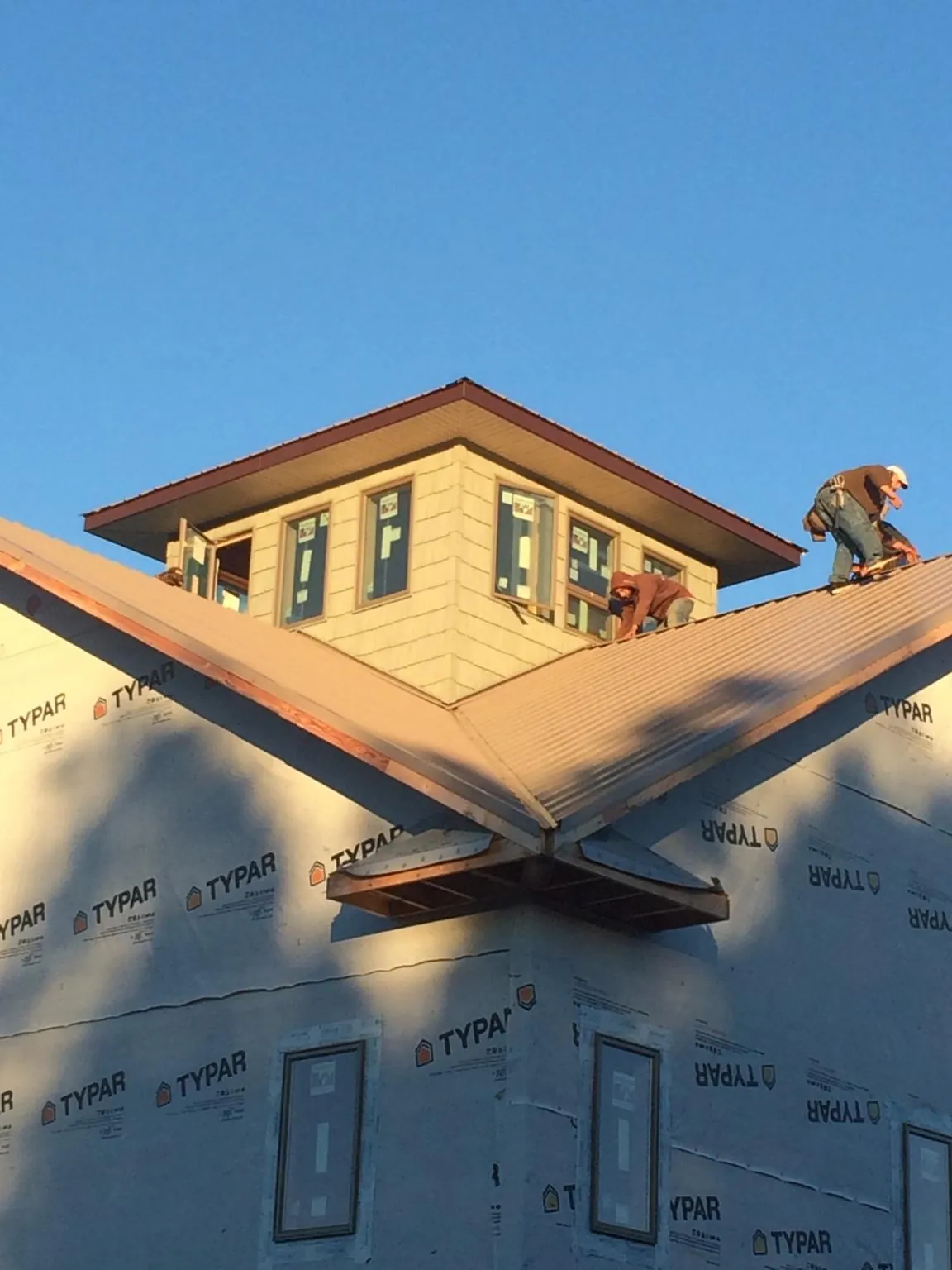 Roofers working around a rooftop cupola on a new metal roof at sunset — Roof Waterproofing in Fort Walton Beach by Roofing Brothers